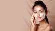 © pariketan - Asian woman with a healthy glowing skin is applying a skincare product.