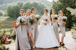 Group portrait of the bride and bridesmaids. A bride in a wedding dress and bridesmaids in silver dresses hold stylish bouquets on their wedding day.