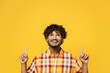 Young happy fun Indian man he wearing shirt casual clothes point index finger overhead on workspace area mock up copy space isolated on plain yellow color background studio portrait Lifestyle concept