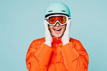 Wall Mural - Young smiling fun skier woman she wear warm padded windbreaker jacket hat ski goggles mask helmet look camera travel rest spend weekend winter season in mountains isolated on plain blue background