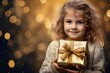 Kleines Mädchen mit blonden Haaren hält ein goldenes Geschenk und lächelt