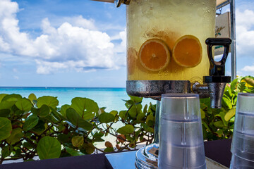 Wall Mural - A fresh water dispenser with fruit on Paynes bay beach with a turquoise sea in the background along the caribbean coast (Barbados).