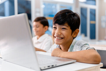 Wall Mural - Portrait school cheerful boy using digital device in school classroom.