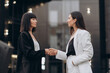 © MZaitsev - Meeting of two business women. Two young women dressed in business suits are shaking hands when meeting on a city street.