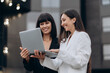 © MZaitsev - Meeting of two business women. Two young women dressed in business suits are discussing a project on a city street.
