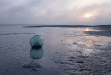 Moody Blue And Purple Sunrise Over The Beach With Hand-blown Glass Float For Fisherman's Net In The Surf 
