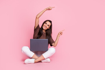 Full body size photo of young lady sit floor woman point fingers novelty web development app with netbook isolated on pink color background
