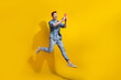 Full length photo of impressed funky man dressed jeans shirt jumping high chatting modern device empty space isolated yellow color background