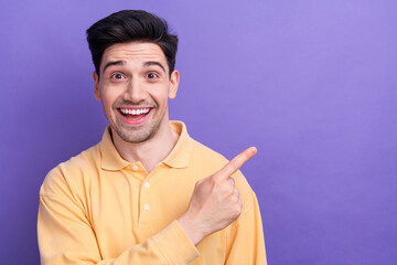 Sticker - Photo of positive excited guy wear yellow polo pointing finger empty space isolated violet color background