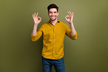 Poster - Portrait of cheerful confident manager man arms fingers demonstrate okey symbol isolated on khaki color background