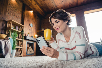 Sticker - Profile photo of stunning peaceful person lying comfy carpet use smart phone hold coffee mug morning daylight indoors