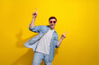 Photo of cheerful good mood man dressed jeans shirt dark spectacles pointing fingers empty space isolated yellow color background