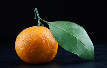 Wall Mural - Ripe juicy tangerine on a dark background.