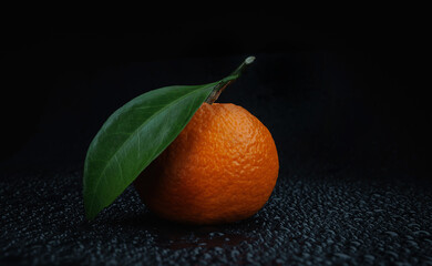 Poster - Ripe juicy tangerine on a black background with water drops.