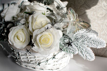 A Bouquet Of White Artificial Roses In A Decorative Basket	