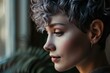 © Georgii - Close-up profile portrait of a young Caucasian woman with short hair dyed grey. Attractive female model with trendy hairstyle and perfect makeup. Beautiful light from the window.