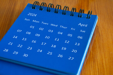 April 2024 table calendar on wooden desk. Time and calendar concept