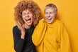 © wayhome.studio  - People and happiness. Indoor photo of young cheerful excited smiling broadly African american and European females standing close to each other on yellow background dressed in casual clothes