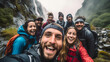 A group of young people standing in front of the waterfalls in nature, wearing backpacks and taking a selfie. Adult friends, males and females smiling at the camera, standing outdoors in nature