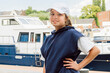 © KiNOVO - Teenage girl in a white baseball cap and blue pullover against the background of a yacht