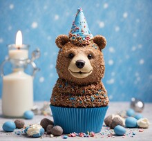 Cupcake With Chocolate Bear And Candle On A Blue Background.