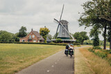 Fototapeta Sawanna - Familie passiert während einer Fahrradtour durch die Niederlande eine typische holländische Windmühle