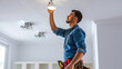 © Studio Nova - A cheerful electrician is attentively installing or repairing a light bulb in a residential setting