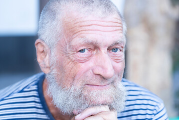 Serious expression of man with blue eyes. 75 year old senior man with white hair looking into the camera