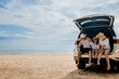 © sorapop - People enjoying road trip sitting down on back their car, Parents and children traveling in holiday at sea beach, family fun in summer vacation on beach blue sky, Happy Family and World Tourism Day