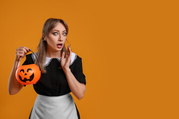 Poster - Emotional woman in scary maid costume with pumpkin bucket on orange background, space for text. Halloween celebration