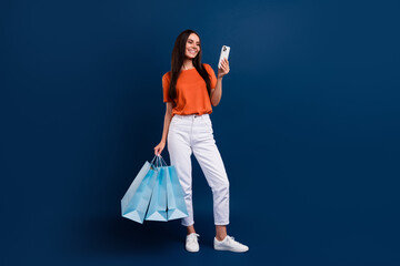 Poster - Full length photo of pretty positive woman dressed orange t-shirt online shopping modern gadget isolated dark blue color background