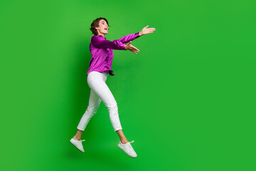 Sticker - Full length profile photo of crazy cheerful person jump run raise arms catch empty space isolated on green color background