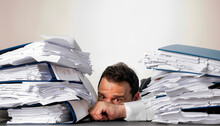 Man With Tie, Buried In Papers At His Work Table In The Office. Work Overload Concept. Stress. Lifestyle.