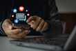© THAWEERAT - Man using social media marketing content on mobile phone with notification icons of like, message and comment above smartphone screen. Friends network community sharing multimedia communication online