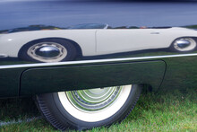 White Classic Car Reflected In The Mirror Like Black Paint Of An American Vintage Classic Car, Black Car Has Fender Skirts And Wide Whitewall Tires