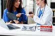 © R Photography - Caucasian and an African American doctor examining a spine and knee bone model, discussing medical details.