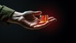 © Anna - a person's hand holding a small glass jar with a red light inside of it on a black background.