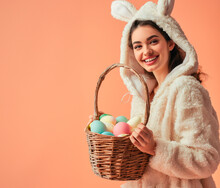 Smiling Woman Holding Basket Of Easter Eggs In Bunny Costume 