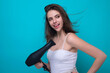 Beautiful young woman using a hair dryer.