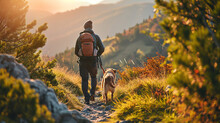 A Man And A Dog Hiking In Beautiful Mountain Landscape, Man With Tourist Backpack Hiking On Spring Wild Field Together With A Dog. The Concept Of The Campaign, Hiking , Spring Traveling And Nature.