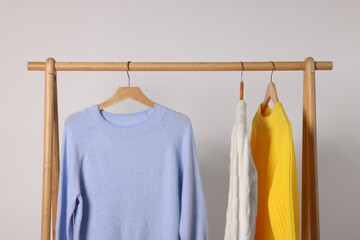 Wall Mural - Rack with different warm sweaters on light background