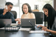 © Phushutter - diverse group of Asian professionals, including middle-aged and mature individuals, gathered around a table in a business setting, discussing documents with focused attention.