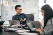 © makibestphoto - diverse group of Asian professionals, including middle-aged and mature individuals, gathered around a table in a business setting, discussing documents with focused attention.