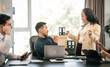 © makibestphoto - diverse group of Asian professionals, including middle-aged and mature individuals, gathered around a table in a business setting, discussing documents with focused attention.