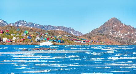 Wall Mural - Melting of a iceberg and pouring water into the sea by the coast of Greenland - Picturesque village on coast of Greenland - Colorful houses in Tasiilaq, East Greenland