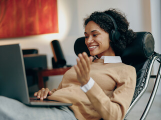 Smiling young female student studies at home remotely on laptop and talking with teacher