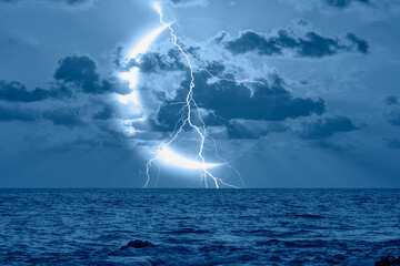 Wall Mural - lightning strikes between blue stormy clouds with crescent moon