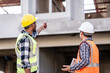 © R Photography - Asian people, two man, holding blueprints Structural engineers examine structural plans for office buildings and housing developments on-site, discussing work at construction site.
