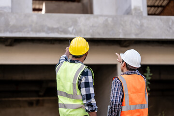 Asian people, two man, holding blueprints Structural engineers examine structural plans for office buildings and housing developments on-site, discussing work at construction site.