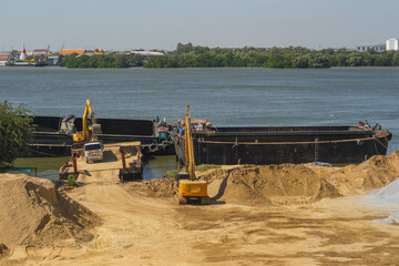 Wall Mural - An excavator is loaded into a river vessel barges sand soil transportation of construction materials and materials along the river.